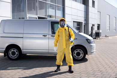 Photo of Pest control worker with spray tank outdoors