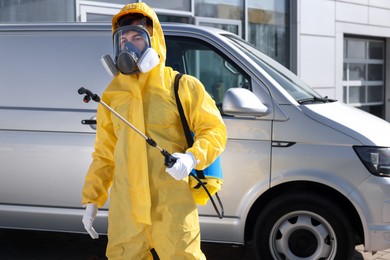 Photo of Pest control worker with spray tank outdoors