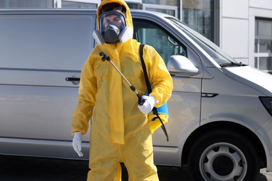 Photo of Pest control worker with spray tank outdoors