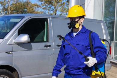 Photo of Pest control worker with spray tank outdoors