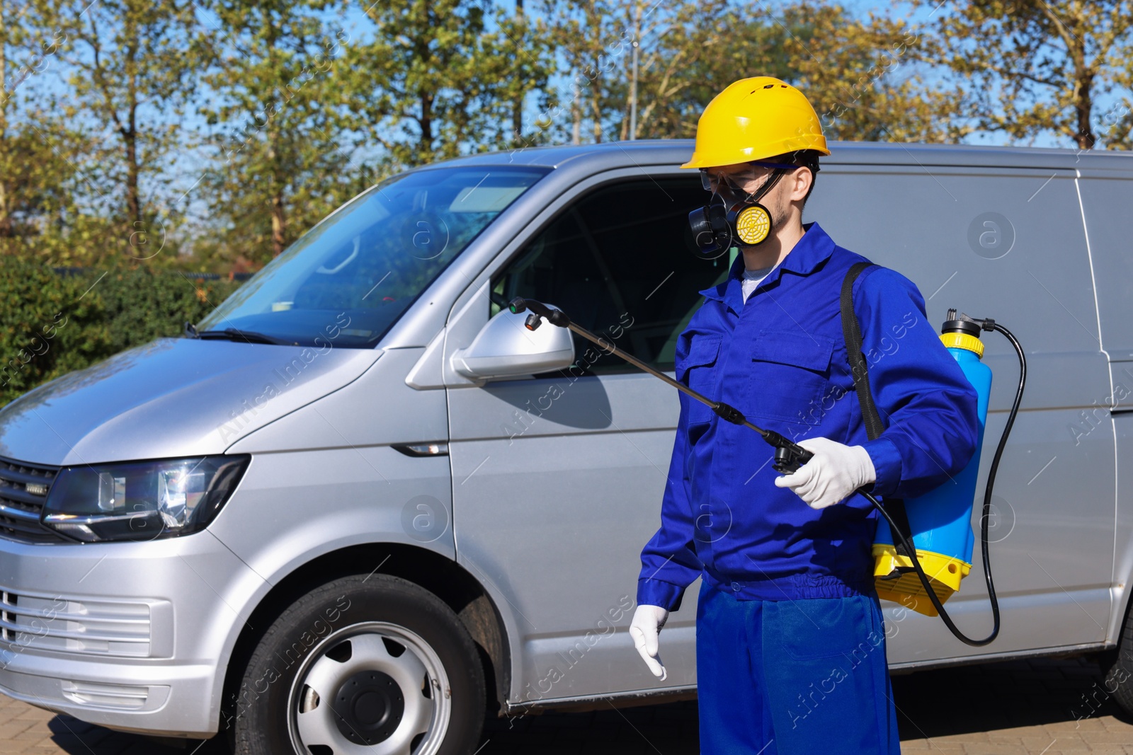 Photo of Pest control worker with spray tank outdoors