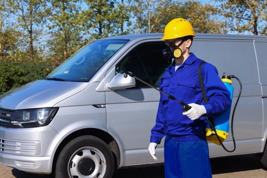 Photo of Pest control worker with spray tank outdoors