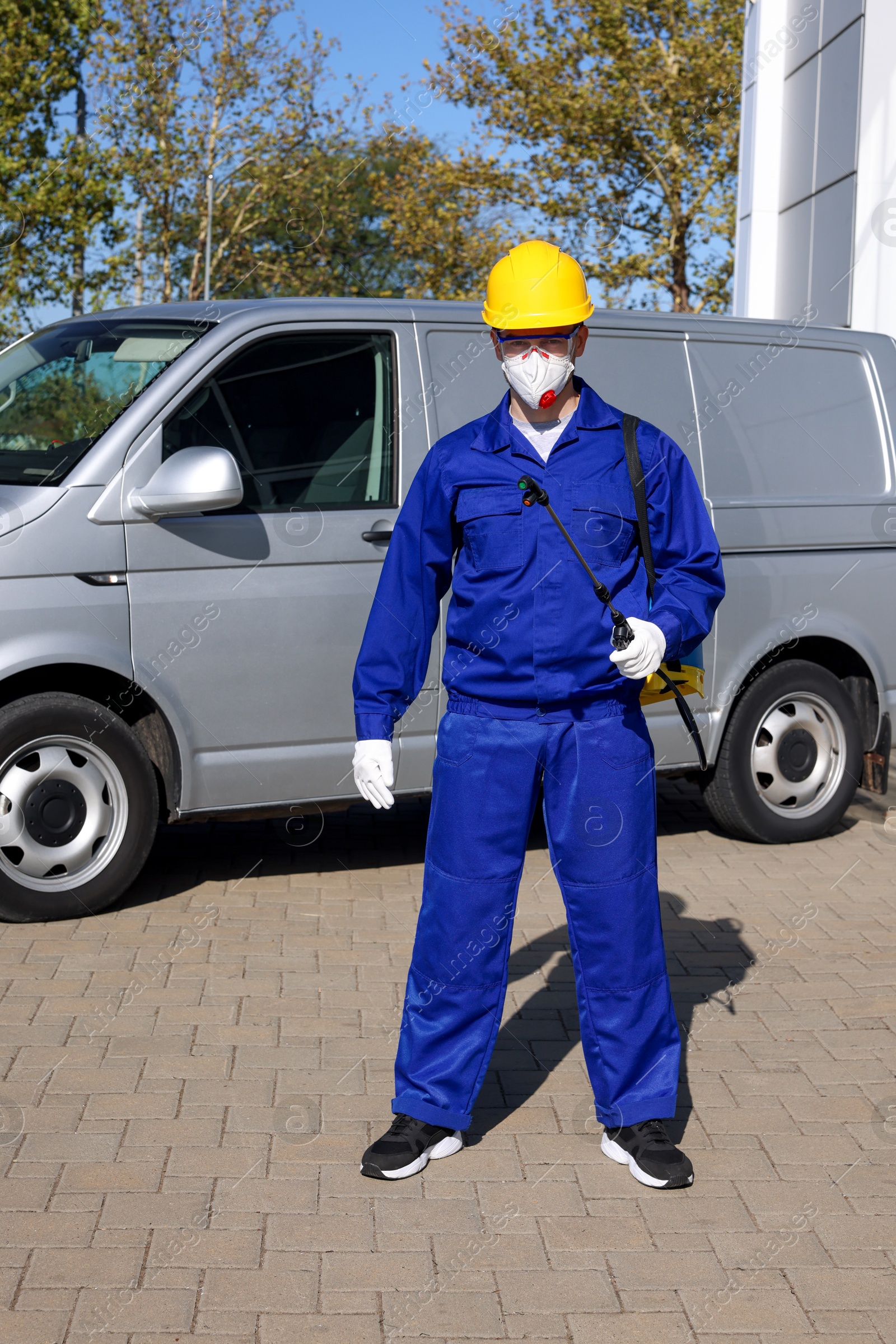 Photo of Pest control worker with spray tank outdoors