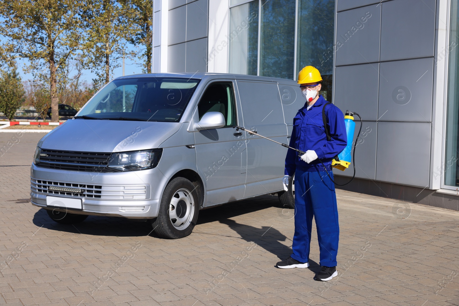 Photo of Pest control worker with spray tank outdoors