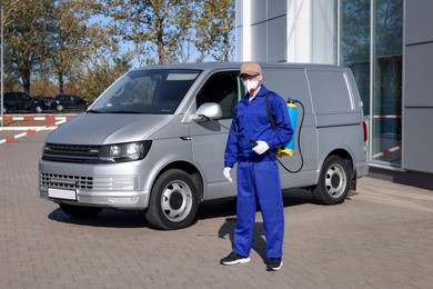 Photo of Pest control worker with spray tank outdoors