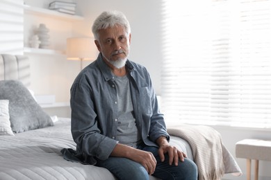 Photo of Lonely senior man sitting on bed at home