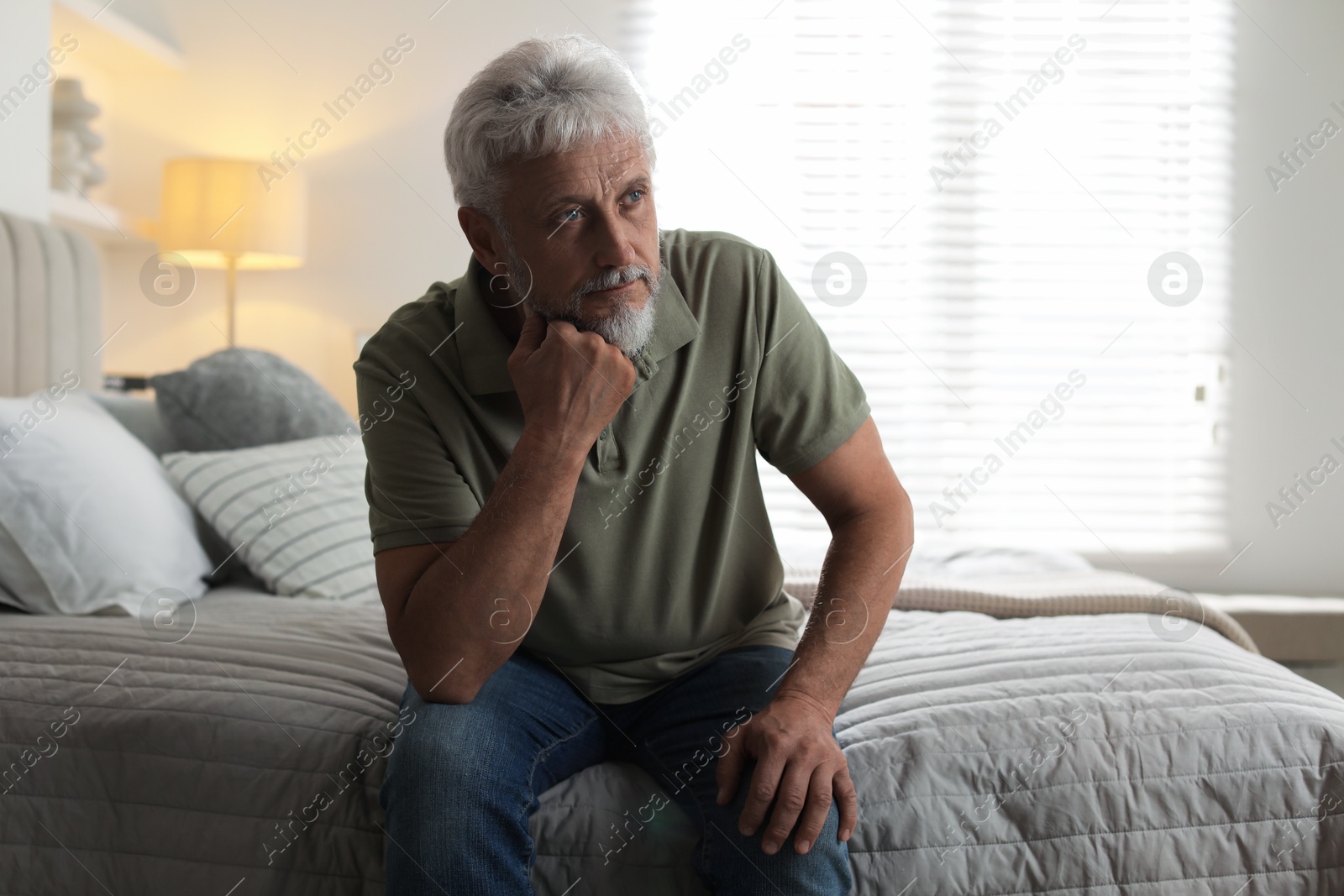 Photo of Lonely senior man sitting on bed at home