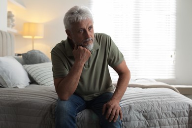 Photo of Lonely senior man sitting on bed at home