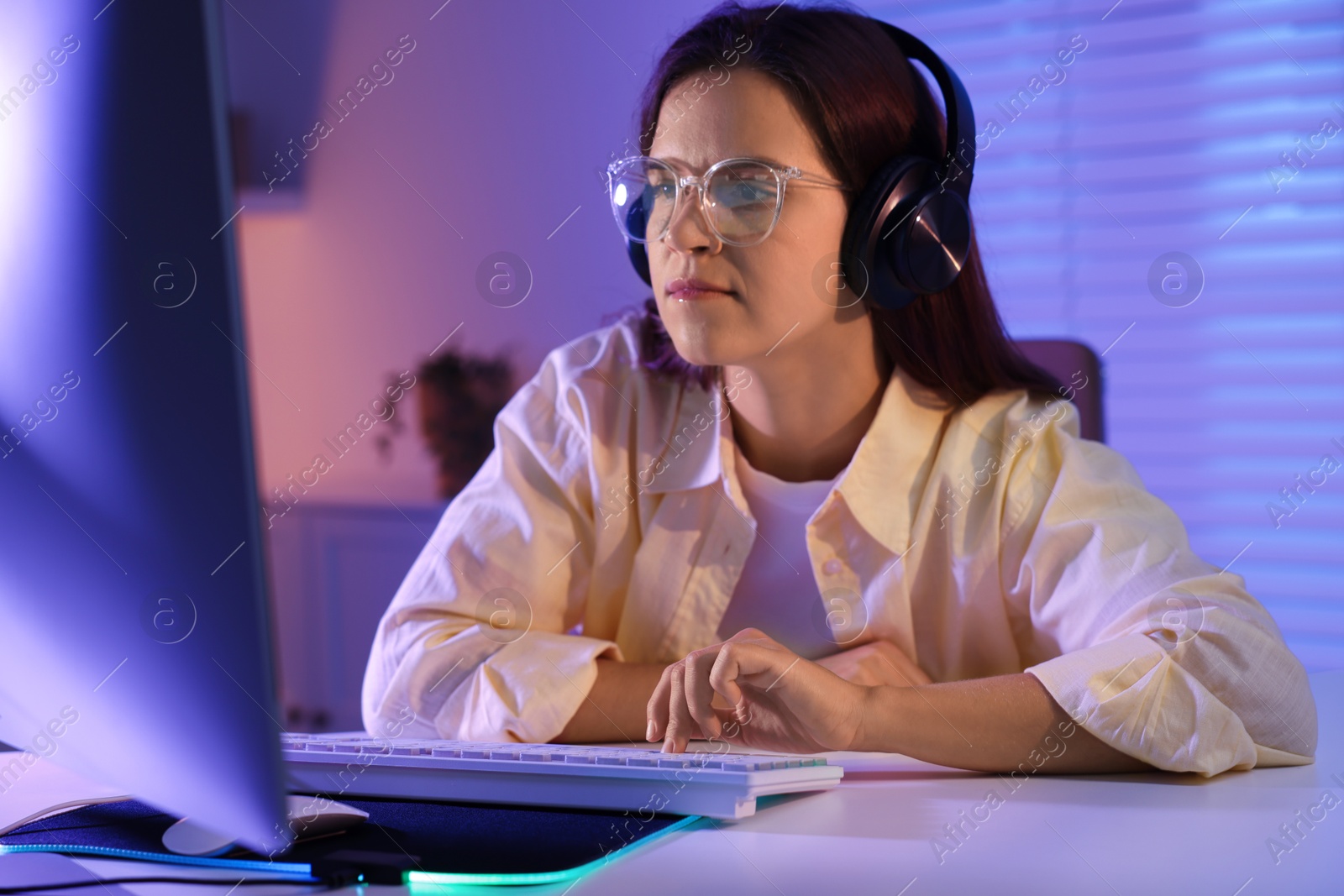 Photo of Woman playing video game with keyboard at table indoors