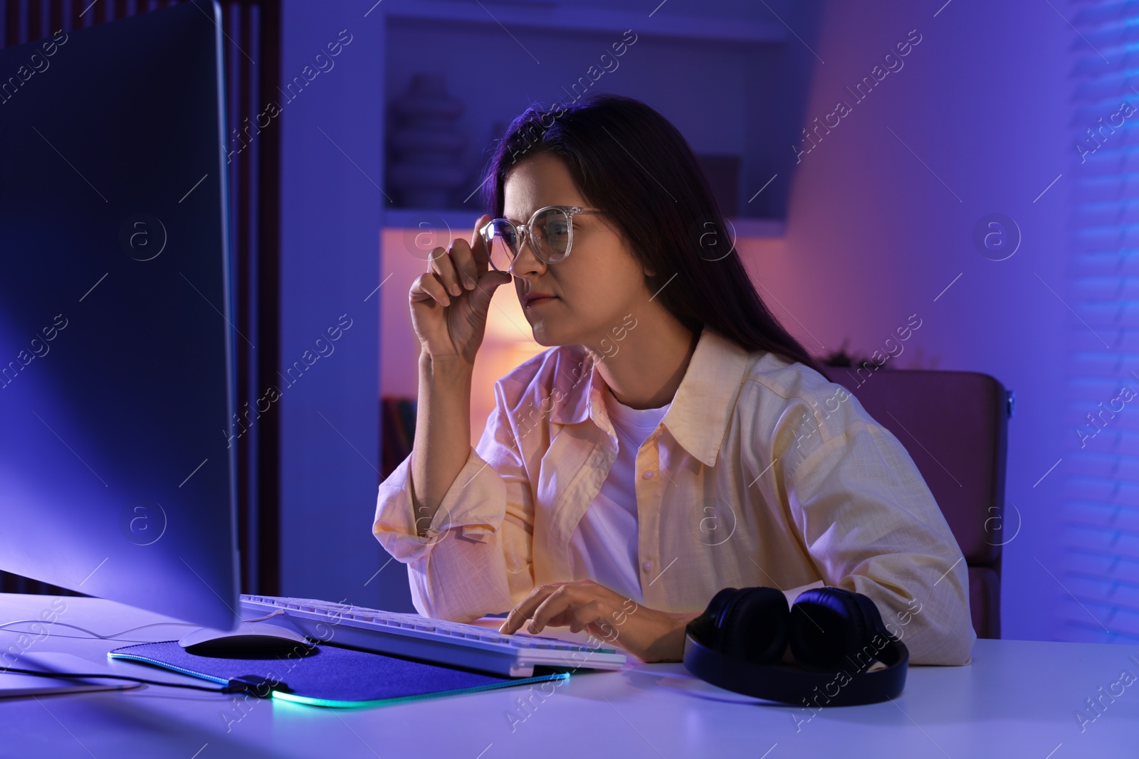 Photo of Woman playing video game with keyboard at table indoors