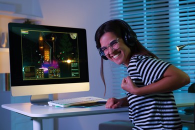 Smiling woman playing video game with keyboard at table indoors