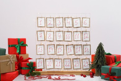 Photo of Handmade advent calendar, gifts and decor on table near light wall. Christmas tradition