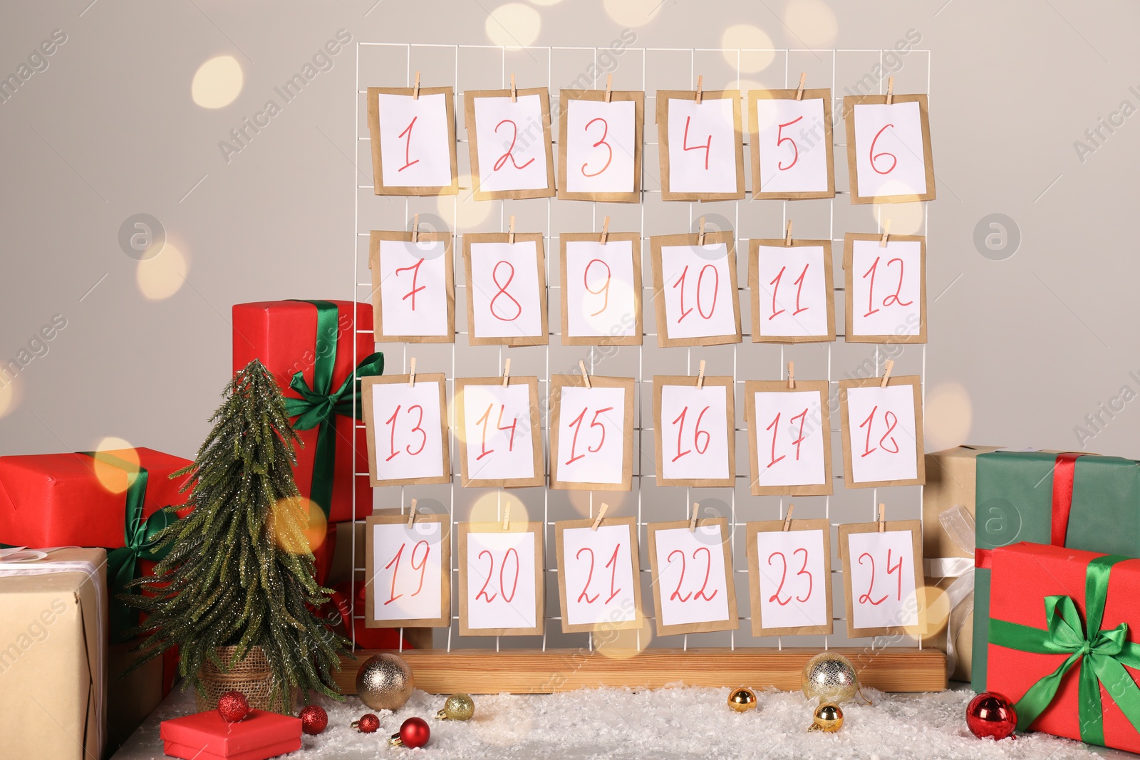 Photo of Handmade advent calendar, gifts and decor on table near light wall. Christmas tradition