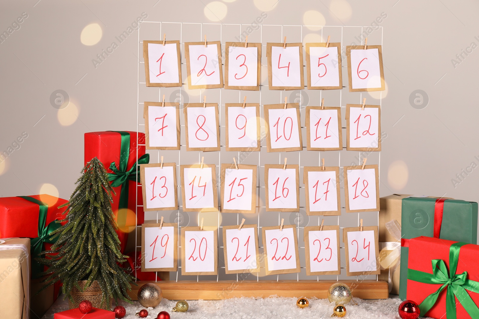 Photo of Handmade advent calendar, gifts and decor on table near light wall. Christmas tradition