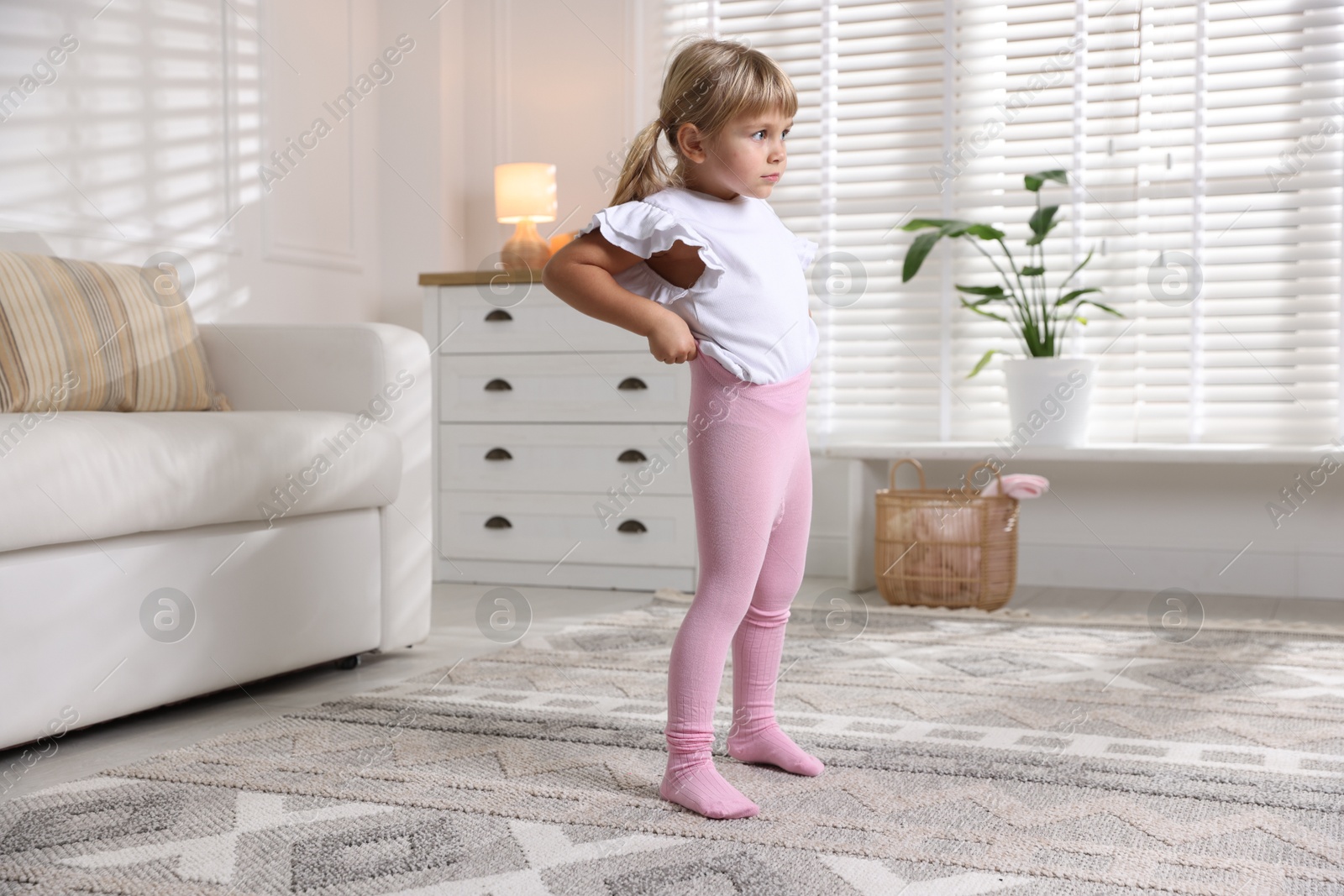 Photo of Little girl putting on soft tights at home