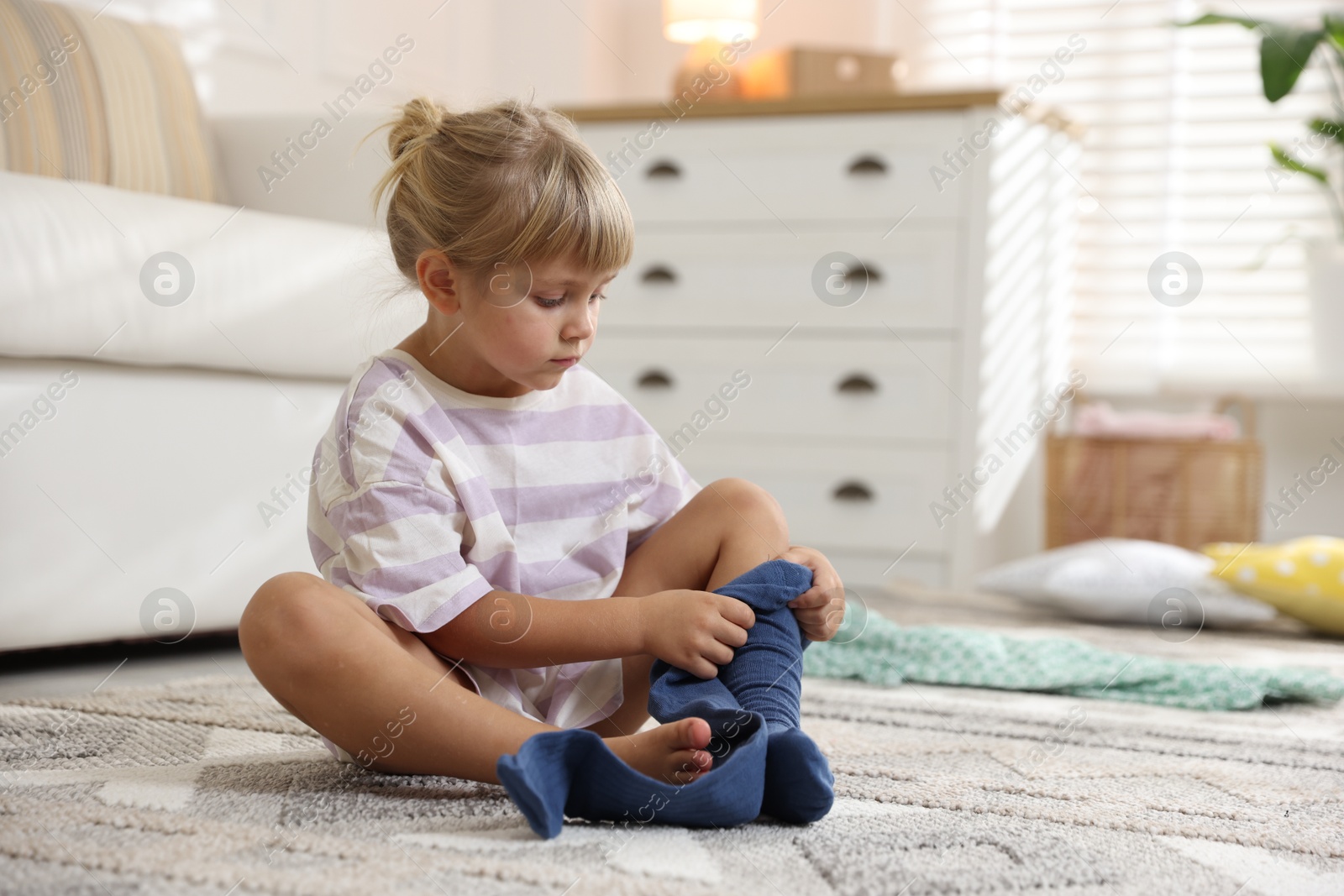 Photo of Little girl putting on soft tights at home. Space for text