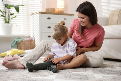 Photo of Mother helping her daughter to put tights on at home