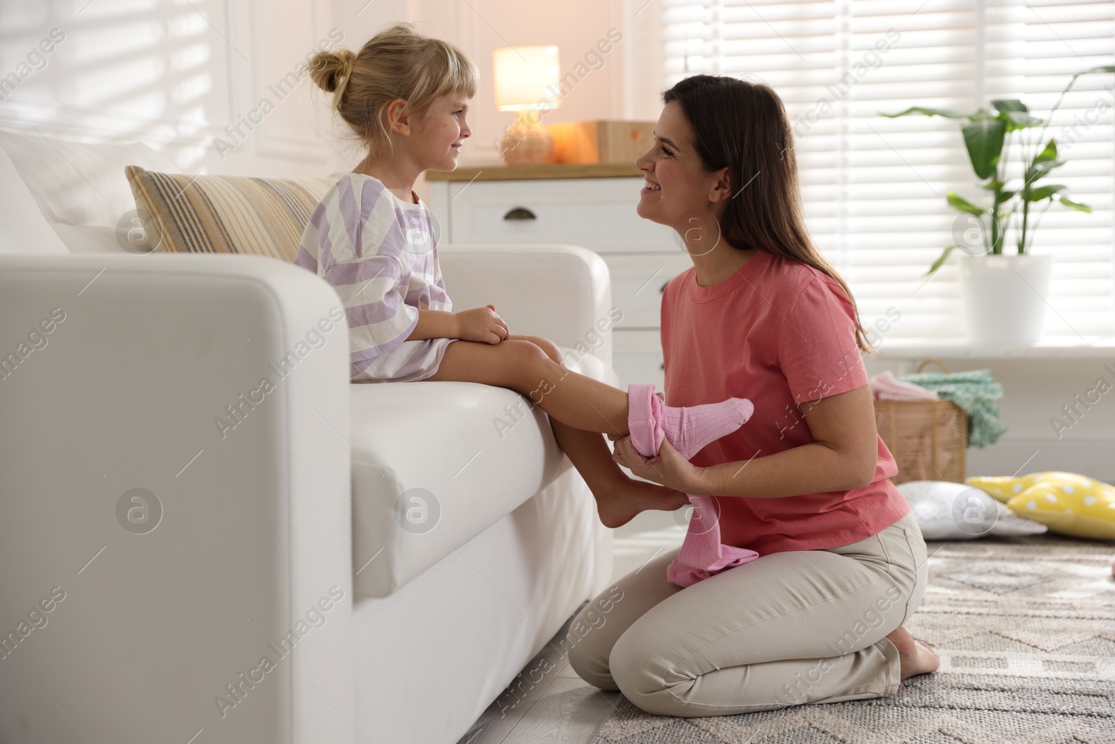 Photo of Mother helping her daughter to put tights on at home