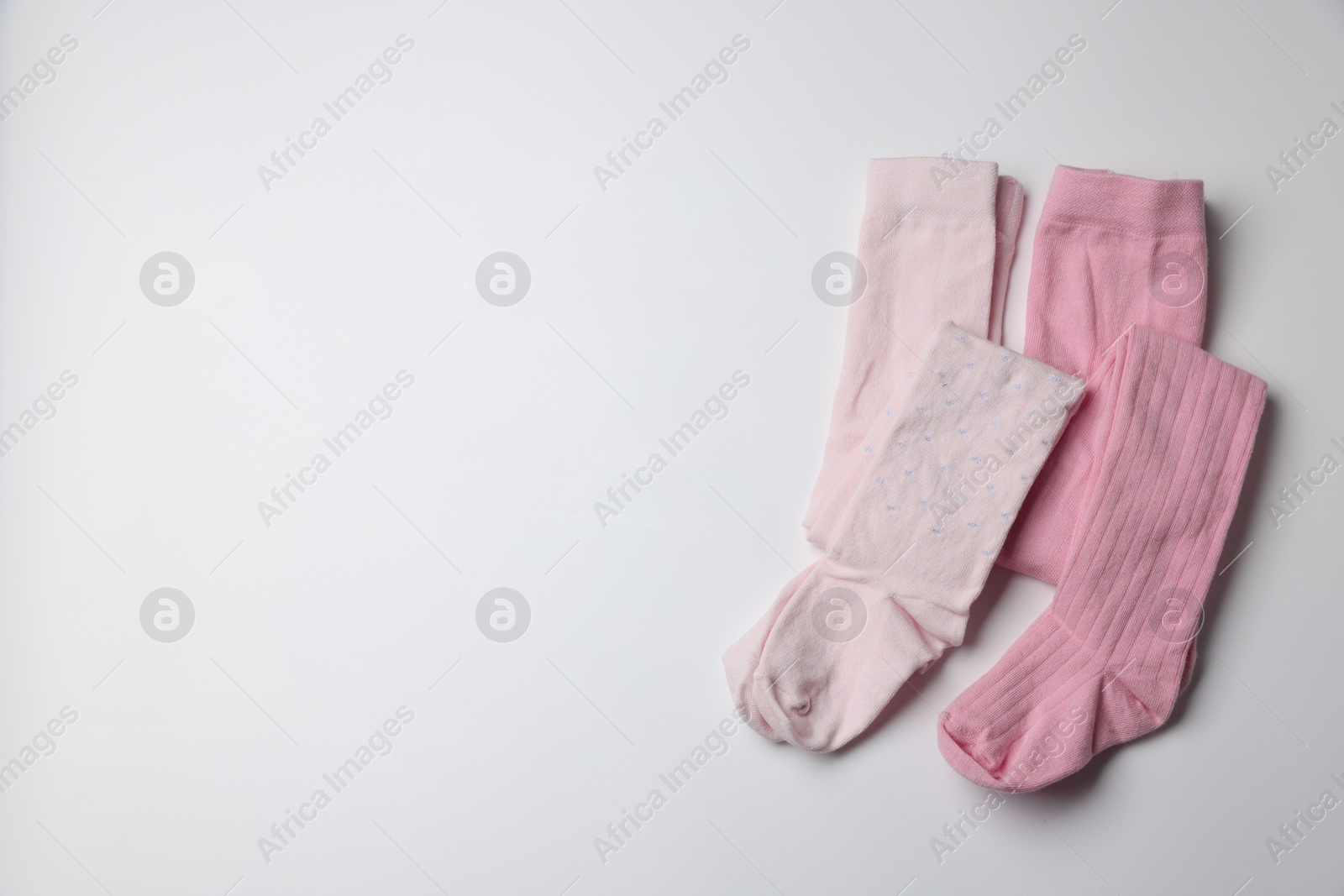 Photo of Beautiful pink child's tights on white background, top view. Space for text