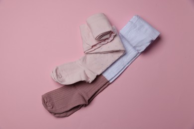 Photo of Different child's tights on pink background, top view