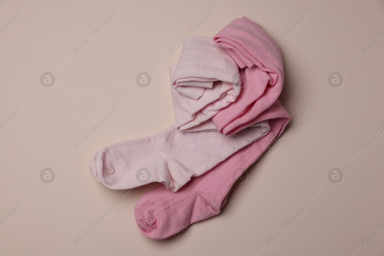 Photo of Beautiful pink child's tights on beige background, top view