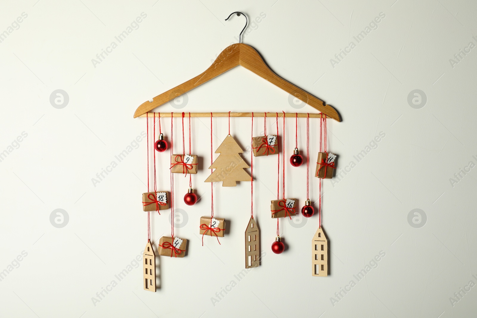 Photo of Handmade advent calendar with decor on hanger against white background. Christmas tradition