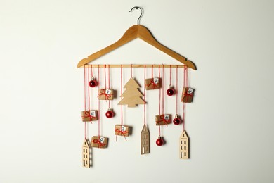 Photo of Handmade advent calendar with decor on hanger against white background. Christmas tradition