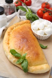 Photo of Tasty vegetarian calzone with basil, mozzarella cheese and tomatoes on table, closeup