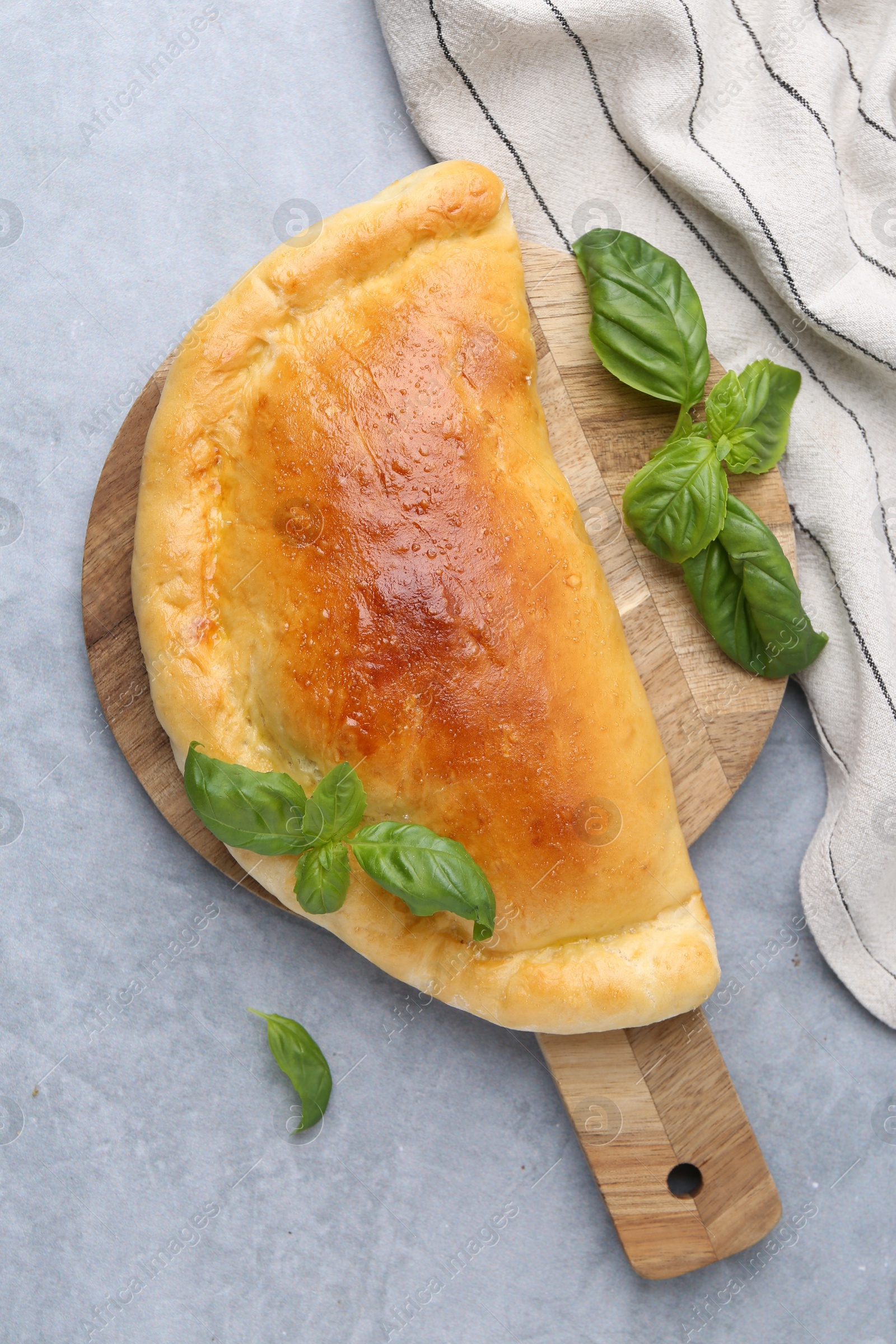 Photo of Tasty vegetarian calzone with basil on grey table, top view