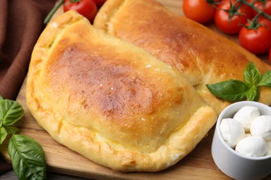 Tasty vegetarian calzones with basil, mozzarella cheese and tomatoes on table, closeup