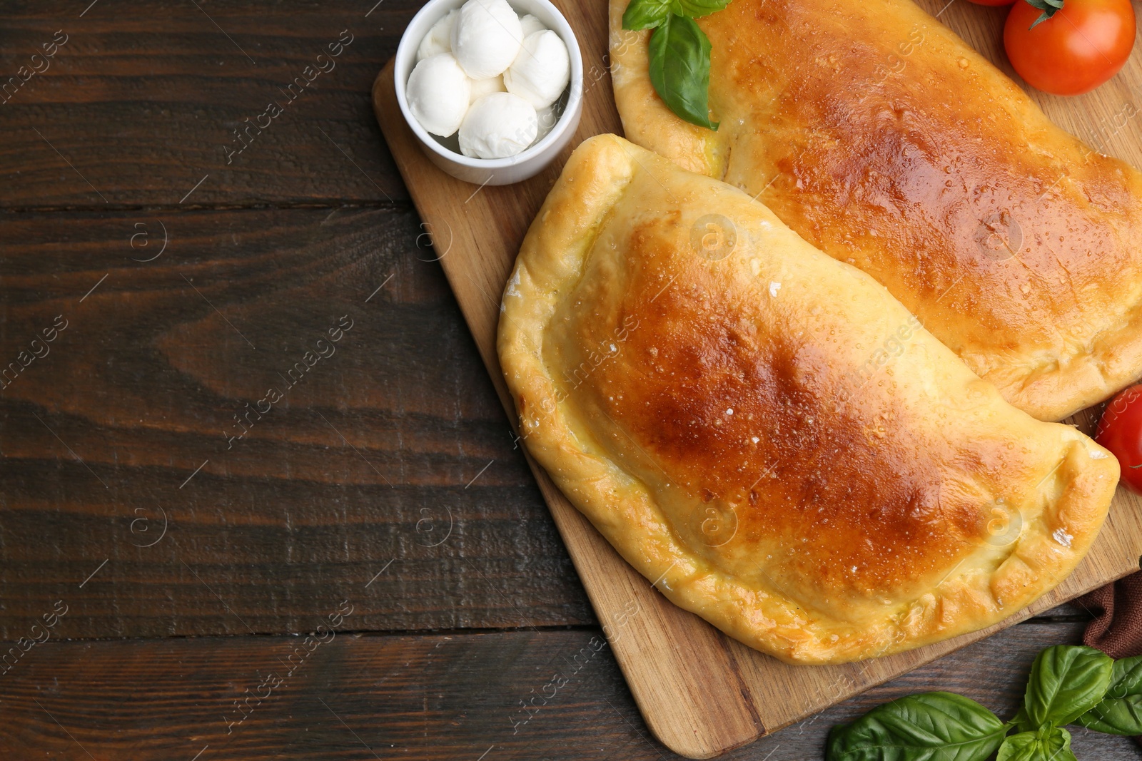 Photo of Tasty vegetarian calzones with basil and mozzarella cheese on wooden table, top view. Space for text