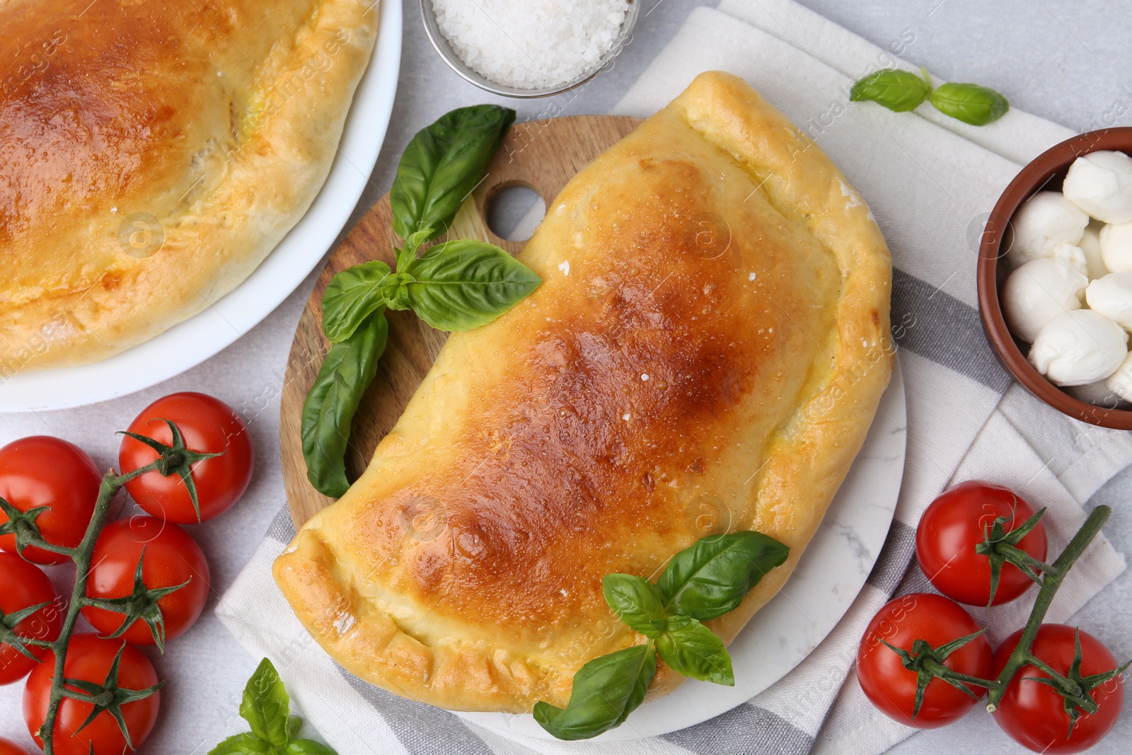 Photo of Tasty vegetarian calzones with basil, tomatoes and mozzarella cheese on light table, flat lay