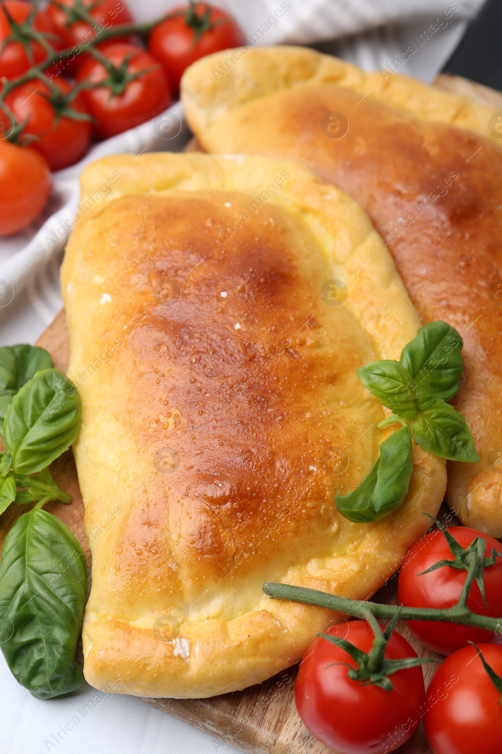 Photo of Tasty vegetarian calzones with basil and tomatoes on table, closeup