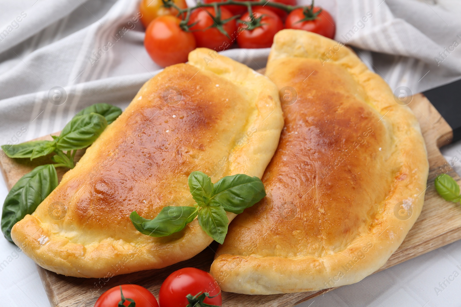 Photo of Tasty vegetarian calzones with basil and tomatoes on table, closeup