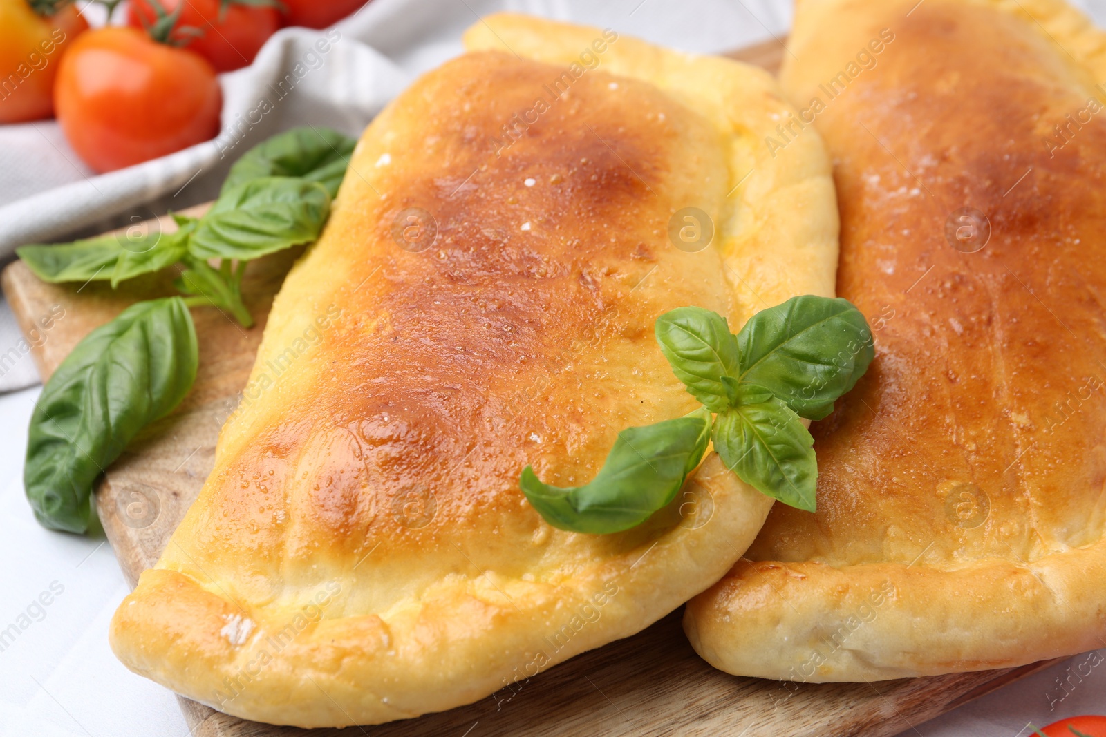 Photo of Tasty vegetarian calzones with basil and tomatoes on table, closeup