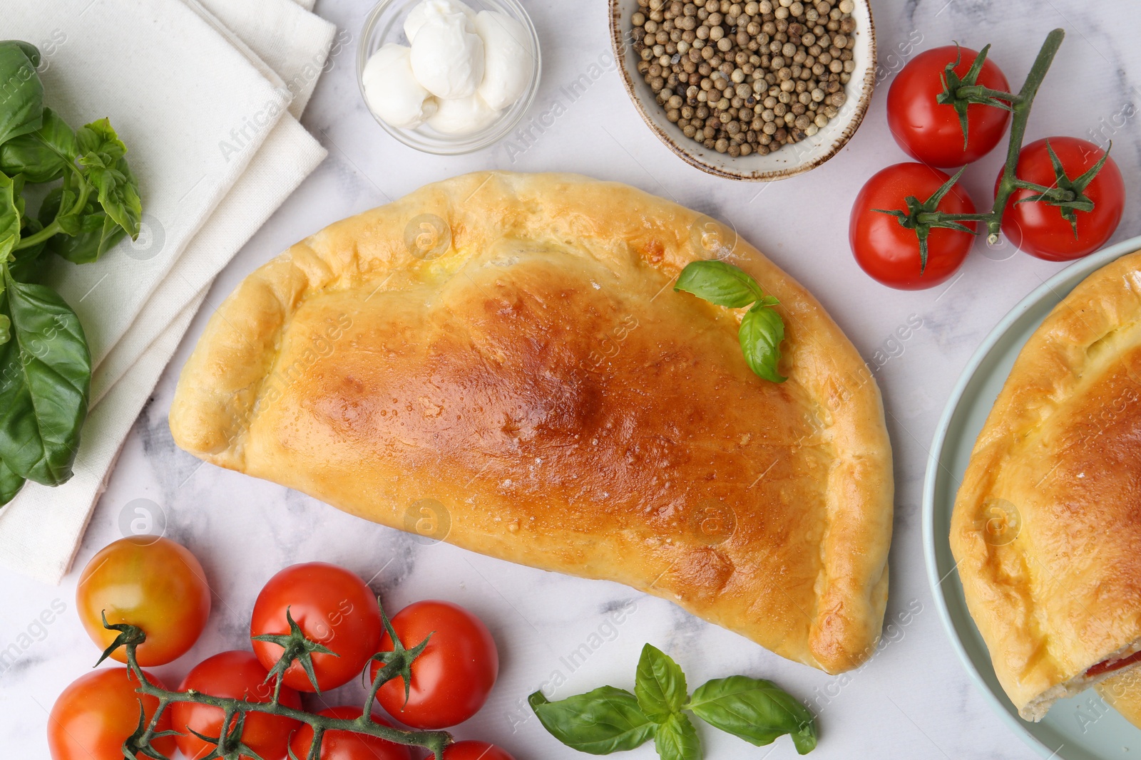 Photo of Tasty vegetarian calzones with tomatoes, mozzarella cheese and spices on white marble table, flat lay