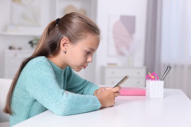 Photo of Girl with incorrect posture using smartphone at white desk indoors