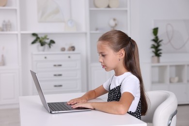 Photo of Girl with correct posture using laptop at white desk indoors