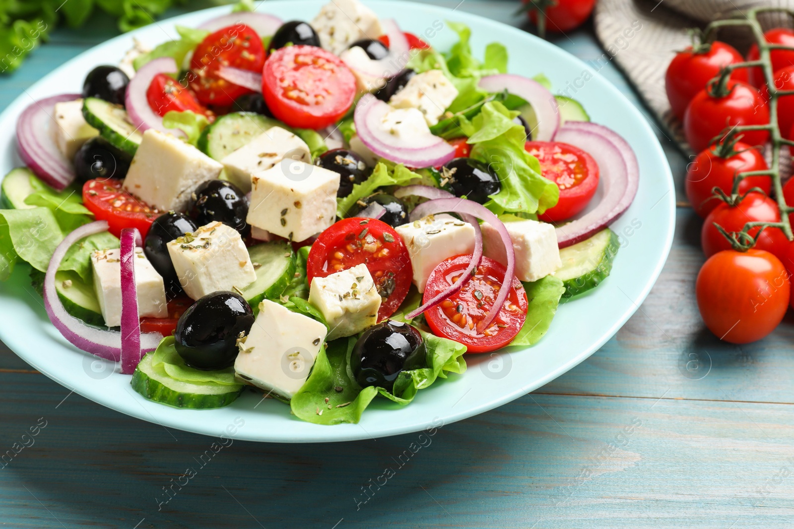 Photo of Delicious salad with feta cheese served on blue wooden table, closeup