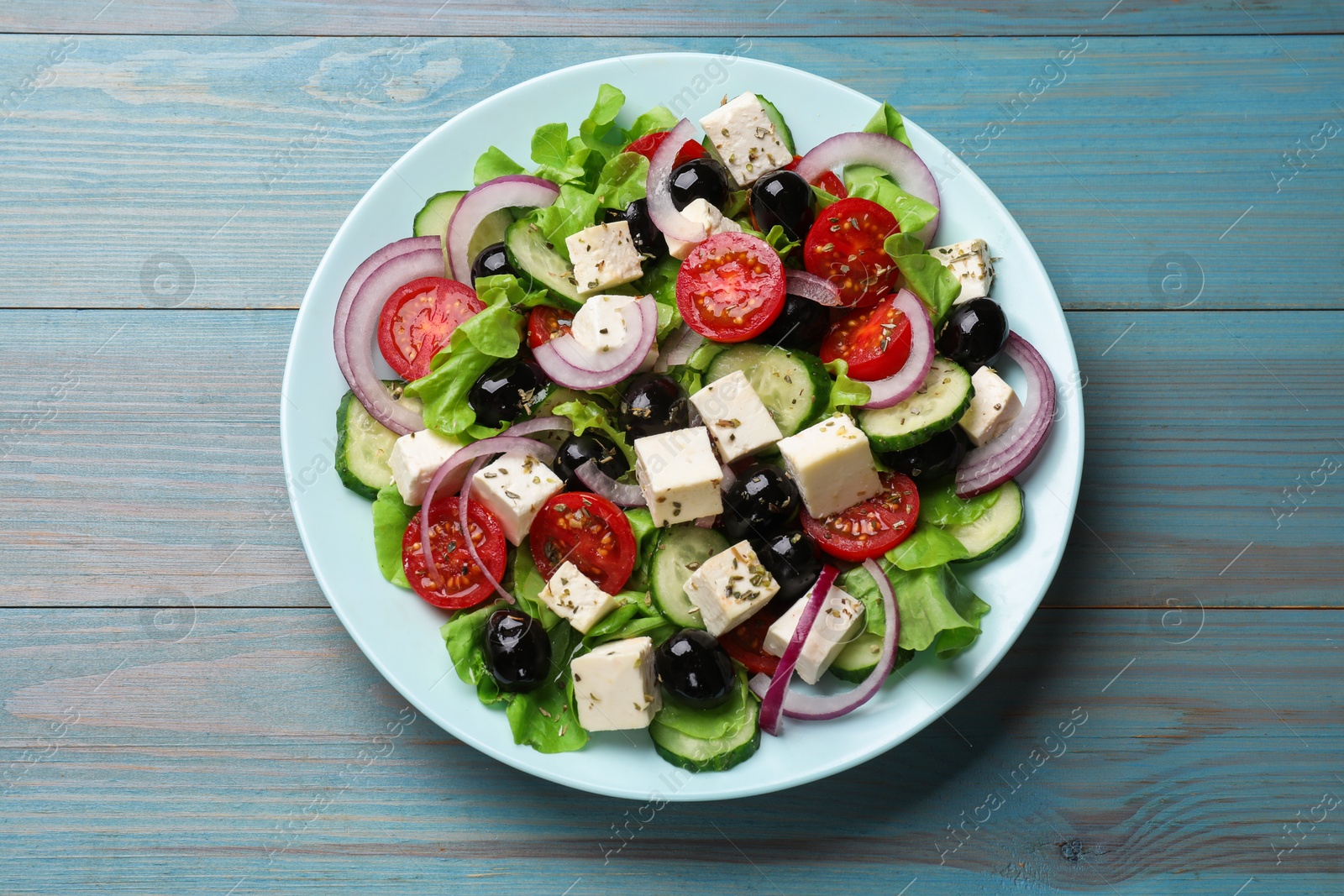 Photo of Delicious salad with feta cheese on blue wooden table, top view