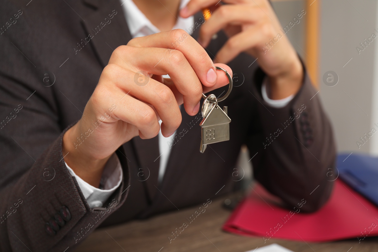 Photo of Real estate agent with house key at table, closeup