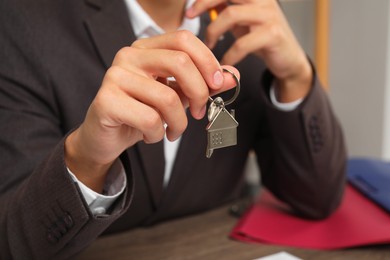 Photo of Real estate agent with house key at table, closeup