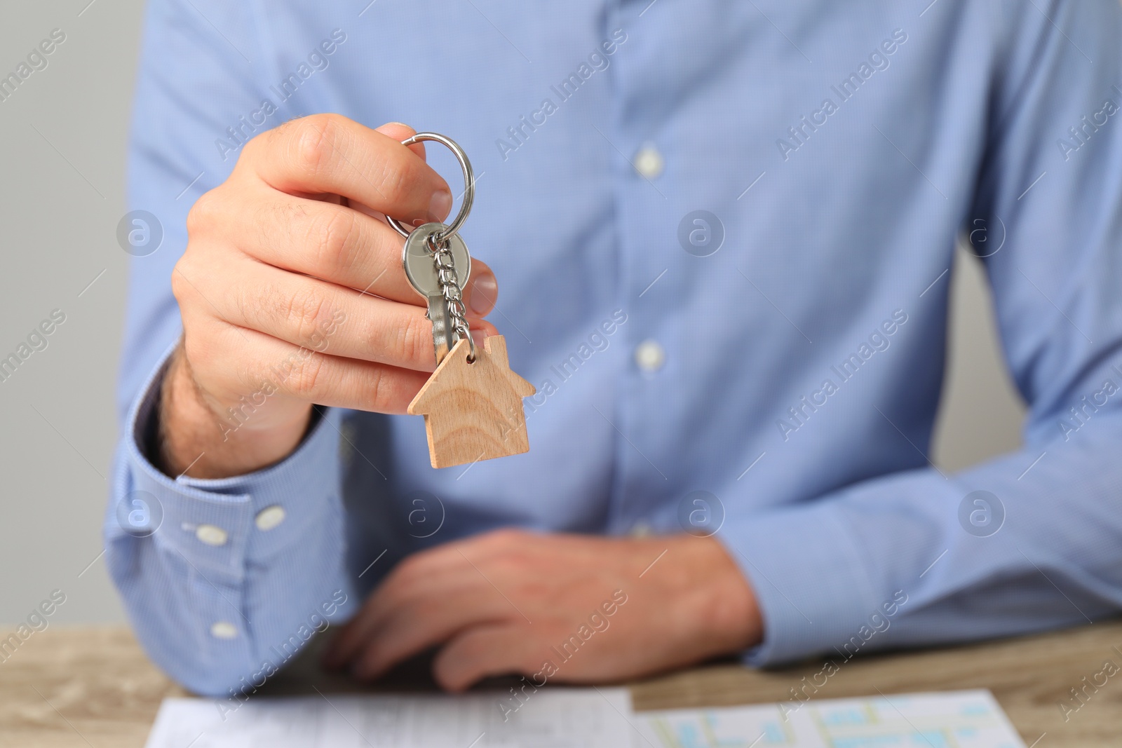 Photo of Real estate agent with house key at table, closeup