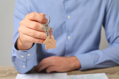 Photo of Real estate agent with house key at table, closeup