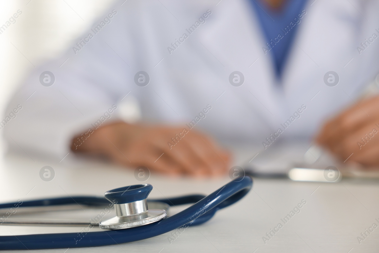 Photo of Doctor working at table, focus on stethoscope