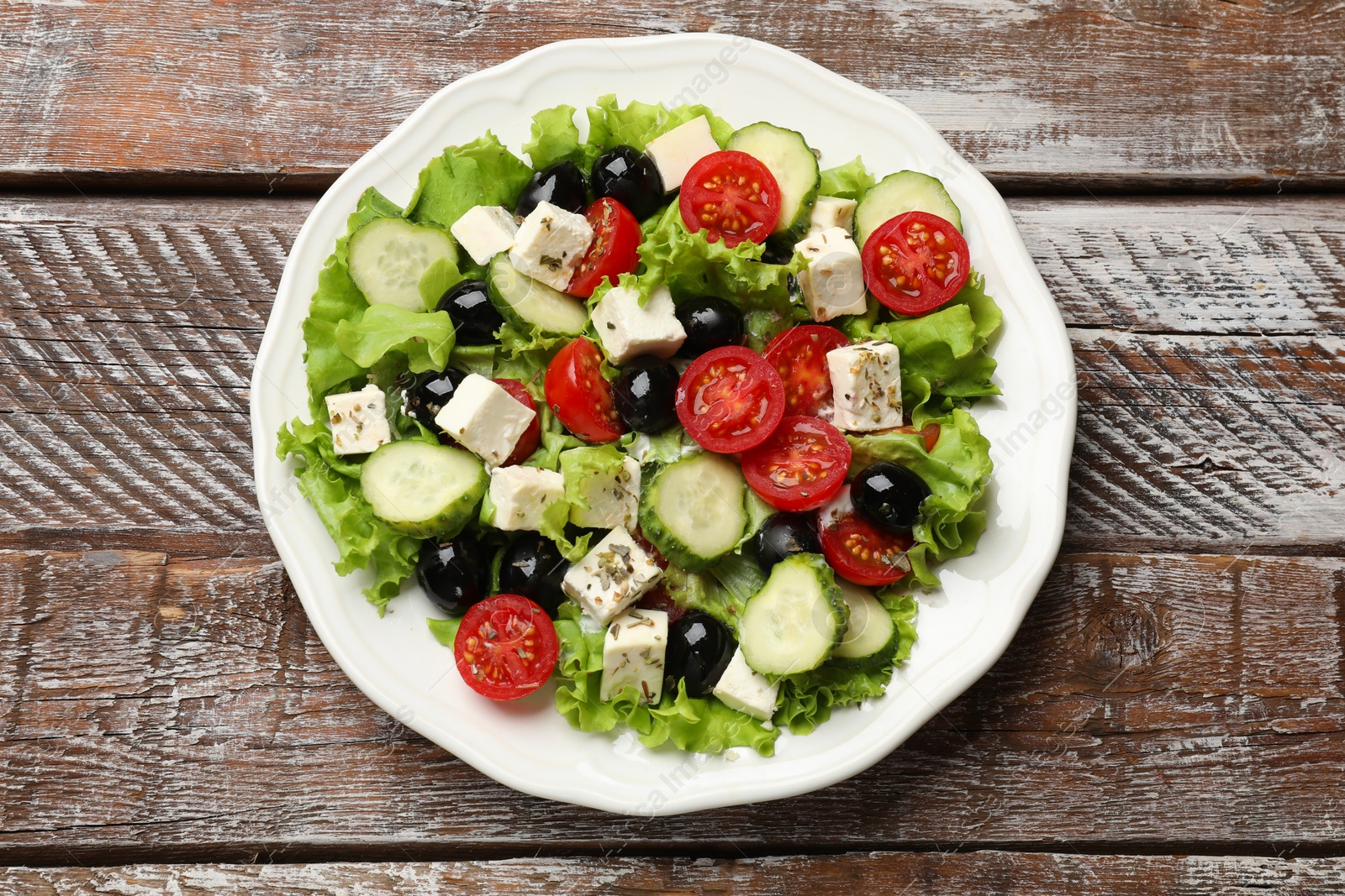 Photo of Delicious salad with feta cheese on wooden table, top view