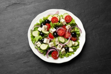 Photo of Delicious salad with feta cheese on dark gray textured table, top view