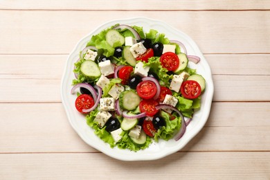 Photo of Delicious salad with feta cheese on wooden table, top view