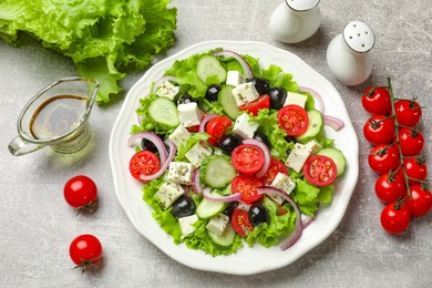 Delicious salad with feta cheese and ingredients on gray textured table, flat lay