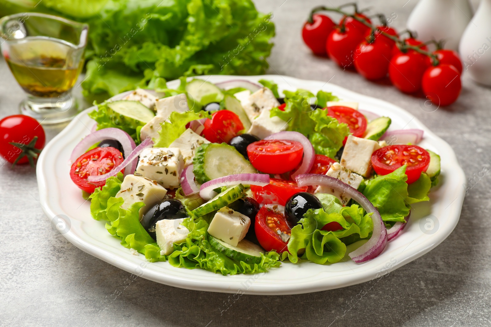 Photo of Delicious salad with feta cheese on gray textured table, closeup